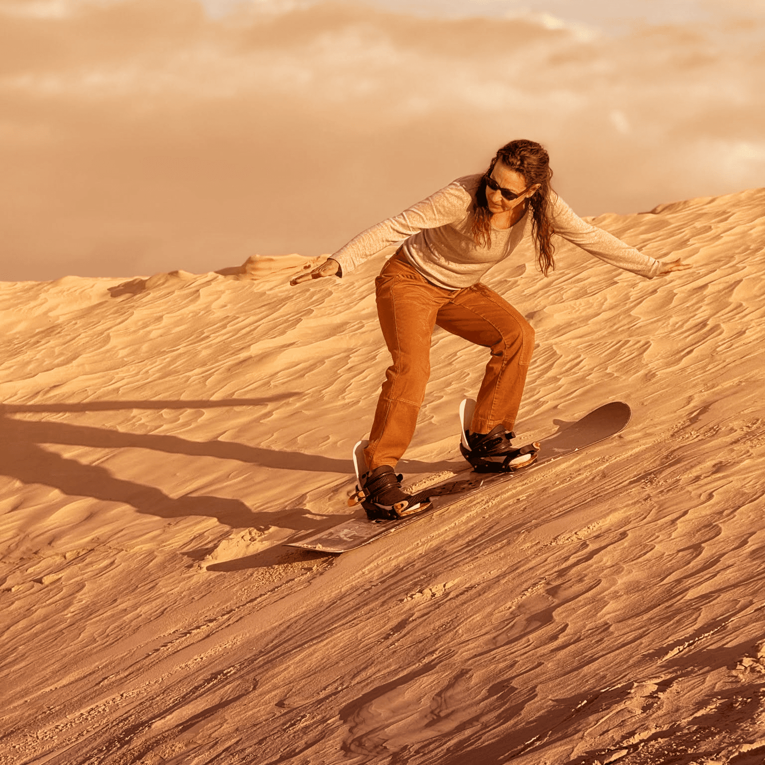 Sandboarder che scende lungo una duna